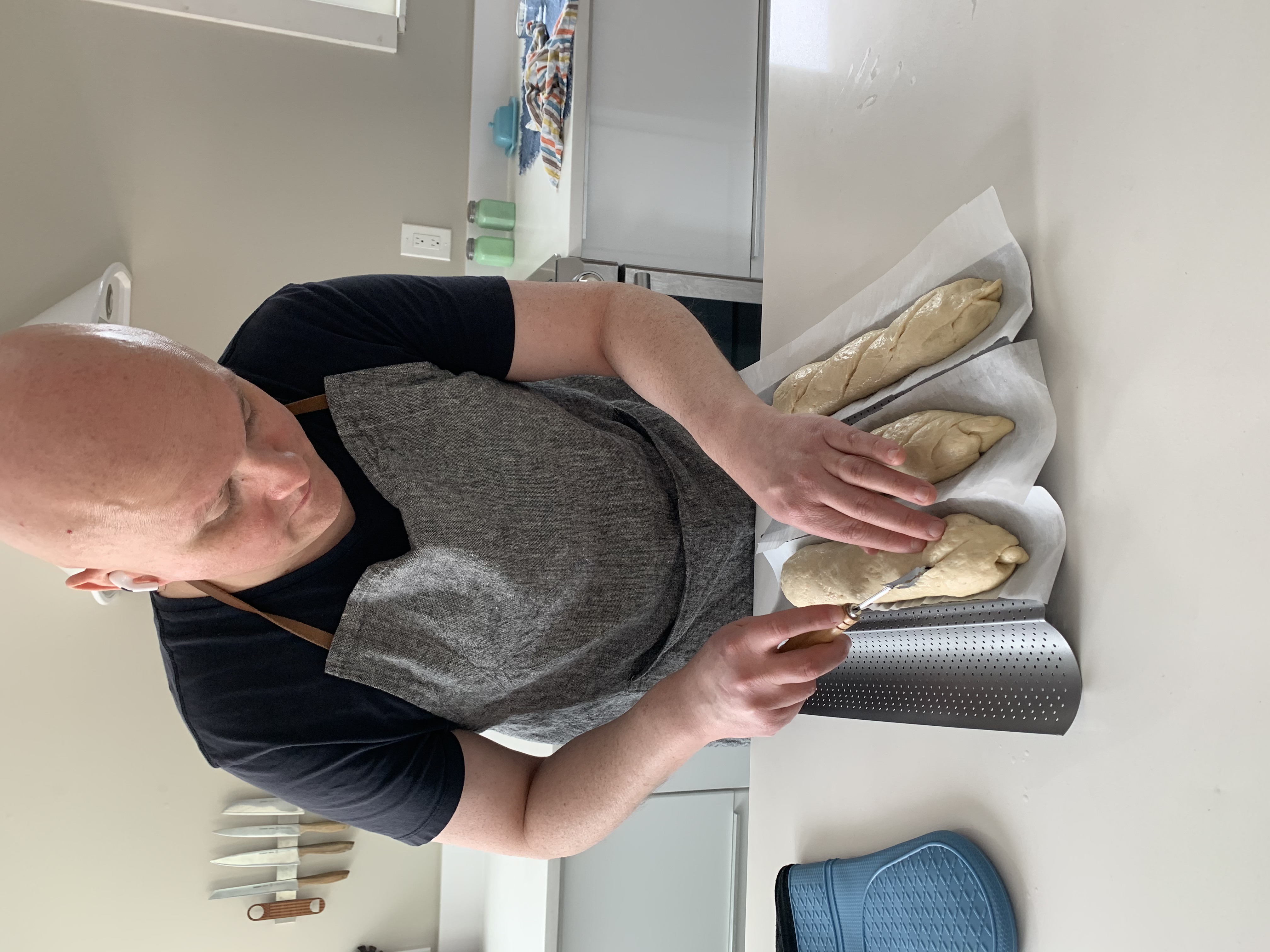 A man making french baggettes in his kitchen.